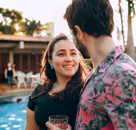 A photo of a man and Latina woman sharing a drink while happily enjoying a conversation